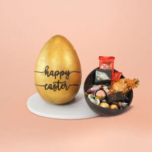 Golden Easter egg with embossed "Happy Easter" text, accompanied by a chocolate shell packed with premium chocolates, KitKat bars, and gold gift pouch – festive CakeSquare hamper.