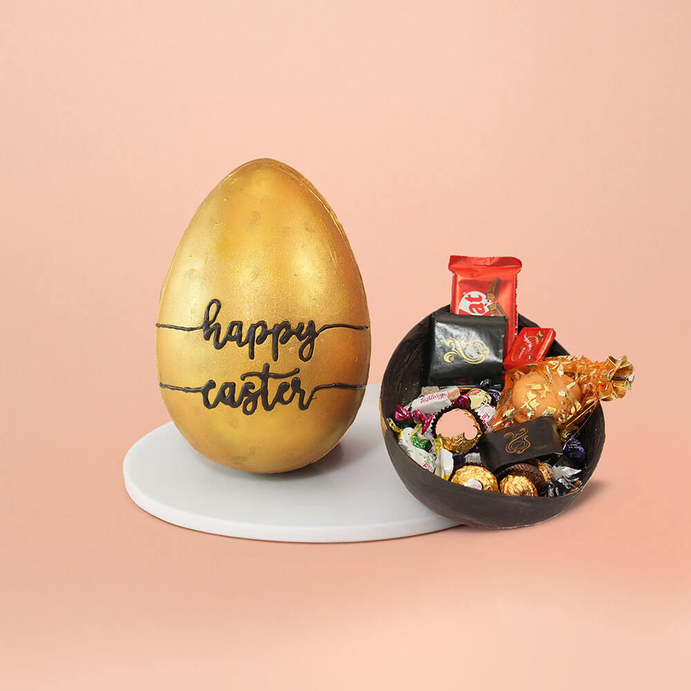 Golden Easter egg with embossed "Happy Easter" text, accompanied by a chocolate shell packed with premium chocolates, KitKat bars, and gold gift pouch – festive CakeSquare hamper.