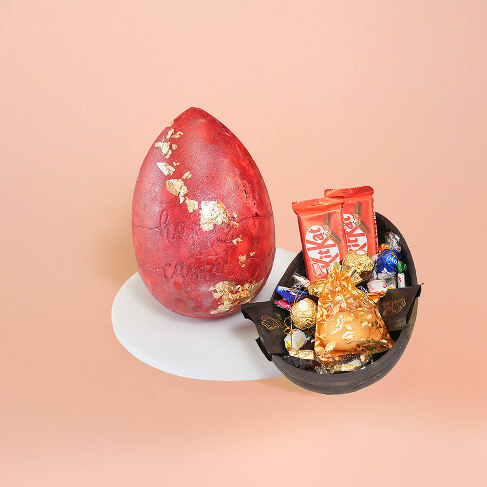 Red Easter egg with gold leaf decoration, filled with KitKat bars, Ferrero Rocher, and assorted chocolates in a decorative chocolate shell – CakeSquare Easter hamper.