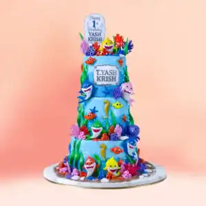 Three tier Baby Shark theme first birthday cake in Chennai with fondant sharks, fish, an octopus, a crab, seahorses and coral on ocean blue tiers from Cake Square.