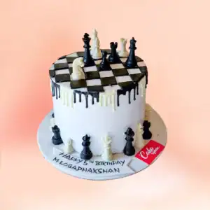 Chess theme birthday cake in Chennai with a black and white drip finish, a checkered chessboard top and fondant chess pieces with a custom name banner from Cake Square.