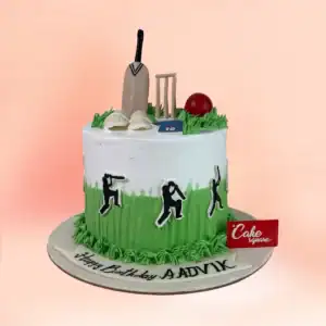 Cricket theme birthday cake for boys in Chennai with a green pitch design, fondant bat, stumps, ball and batting pads and a custom name banner from Cake Square.