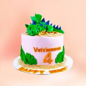 Dragon theme birthday cake in Chennai with a sleeping green dragon figure resting on gold coins, jungle leaf detailing and a custom name and age topper from Cake Square.