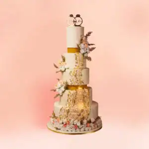 Five tier ivory luxury wedding cake in Chennai with a glowing gold geode crystal panel, gold bands, hand piped gold filigree, peach and white roses and a Mr and Mrs rings topper from Cake Square.
