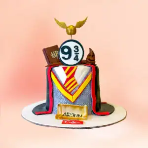 Harry Potter theme birthday cake in Chennai with a Gryffindor tie and cloak design, a Golden Snitch topper, Sorting Hat and Platform Nine and Three Quarters sign from Cake Square.