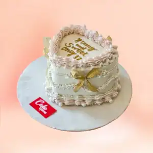 Heart shaped vintage buttercream cake in Chennai with cream and gold Lambeth piping, a pearl border, gold bow and custom Sweet 16 message plaque from Cake Square.