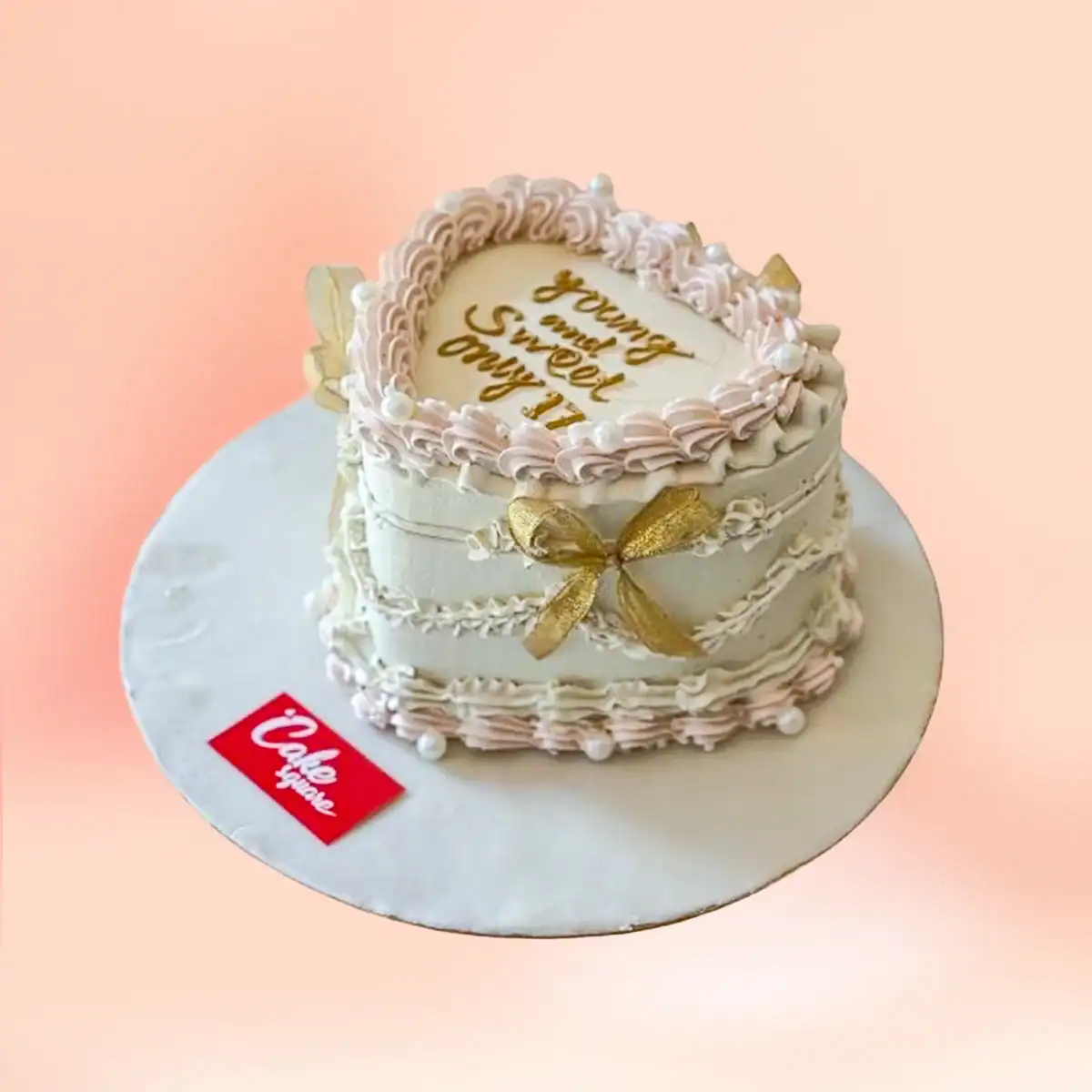 Heart shaped vintage buttercream cake in Chennai with cream and gold Lambeth piping, a pearl border, gold bow and custom Sweet 16 message plaque from Cake Square.