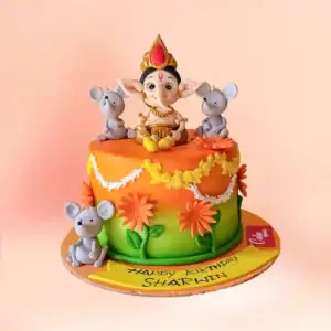 Lord Ganesha theme birthday cake in Chennai with orange to green ombre fondant, a Ganesha figure, marigold garland and a custom Happy Birthday name banner from Cake Square.