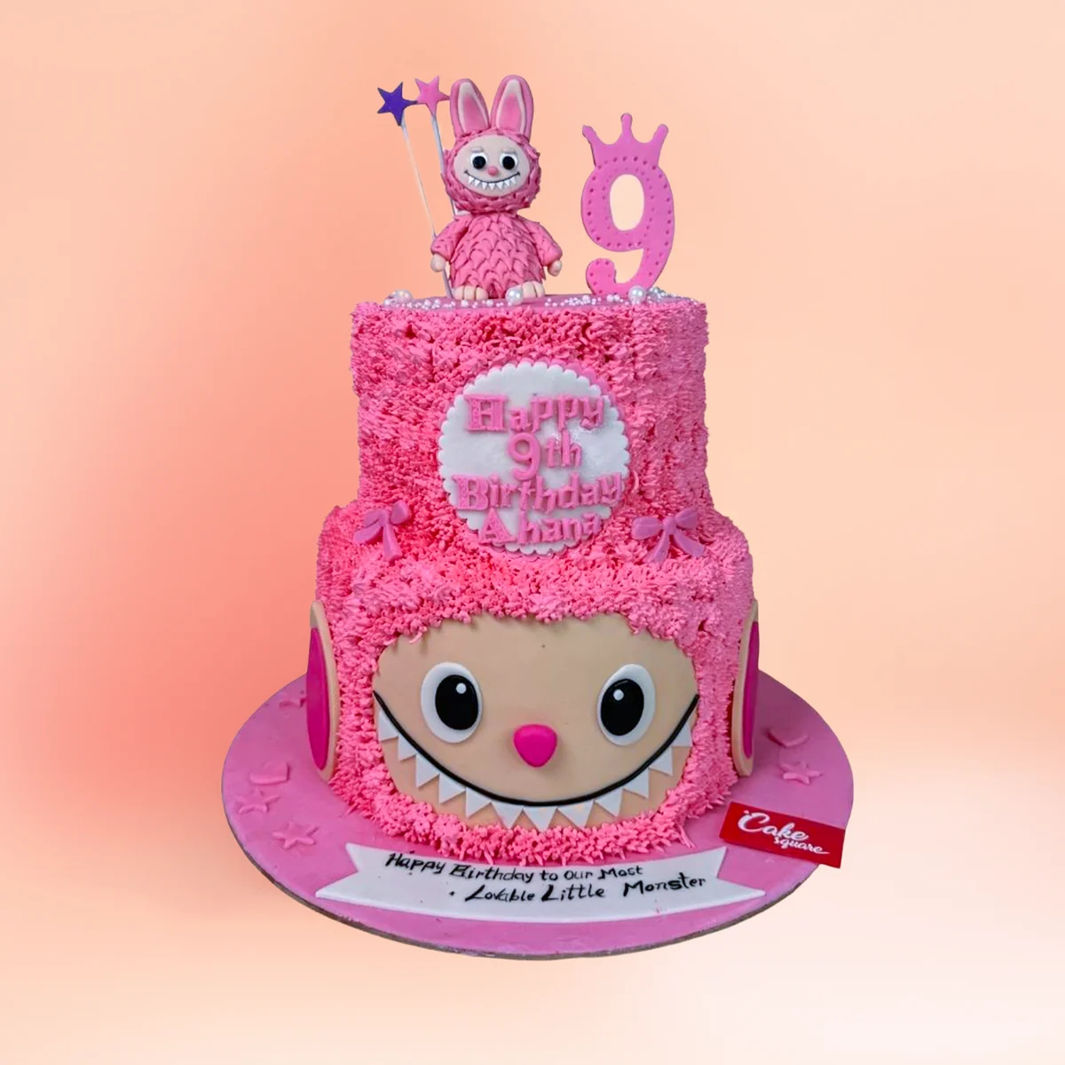 Two tier pink Labubu theme birthday cake in Chennai with textured pink buttercream, a Labubu figure topper and a custom name and age plaque from Cake Square.