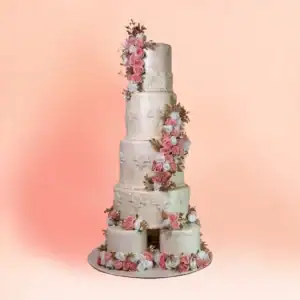 Five tier ivory floral wedding cake in Chennai with a cascade of pink and white sugar roses and gold leaves from top to base, damask piping and a split base tier on a white board from Cake Square.