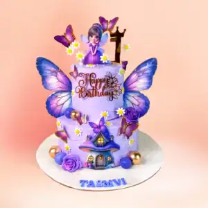 Purple fairy theme first birthday cake in Chennai with a winged fairy figure, lilac butterflies and a toadstool house on a two tier lilac buttercream cake from Cake Square.