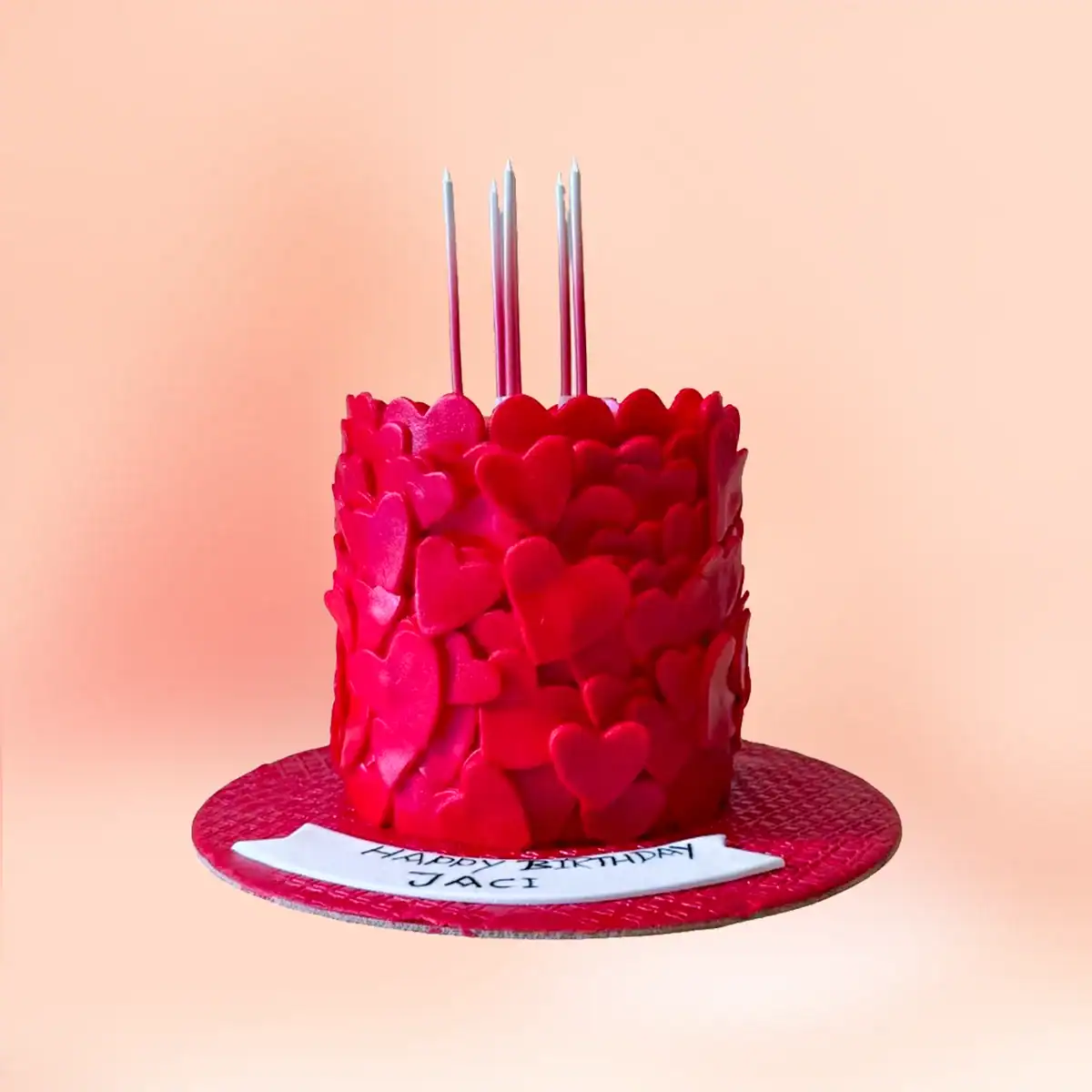 Red heart fondant anniversary cake in Chennai covered in overlapping fondant hearts with a custom name banner, made for anniversaries and Valentine's Day by Cake Square.
