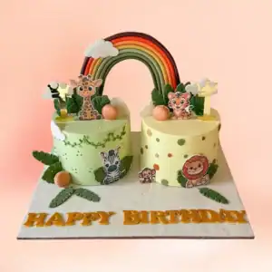 Twins jungle and rainbow theme first birthday cake in Chennai, two cakes joined by a fondant rainbow with giraffe, tiger, zebra and lion figures from Cake Square.